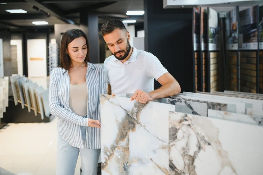 Casal analisando amostras grandes de m&aacute;rmore em uma loja de revestimentos.