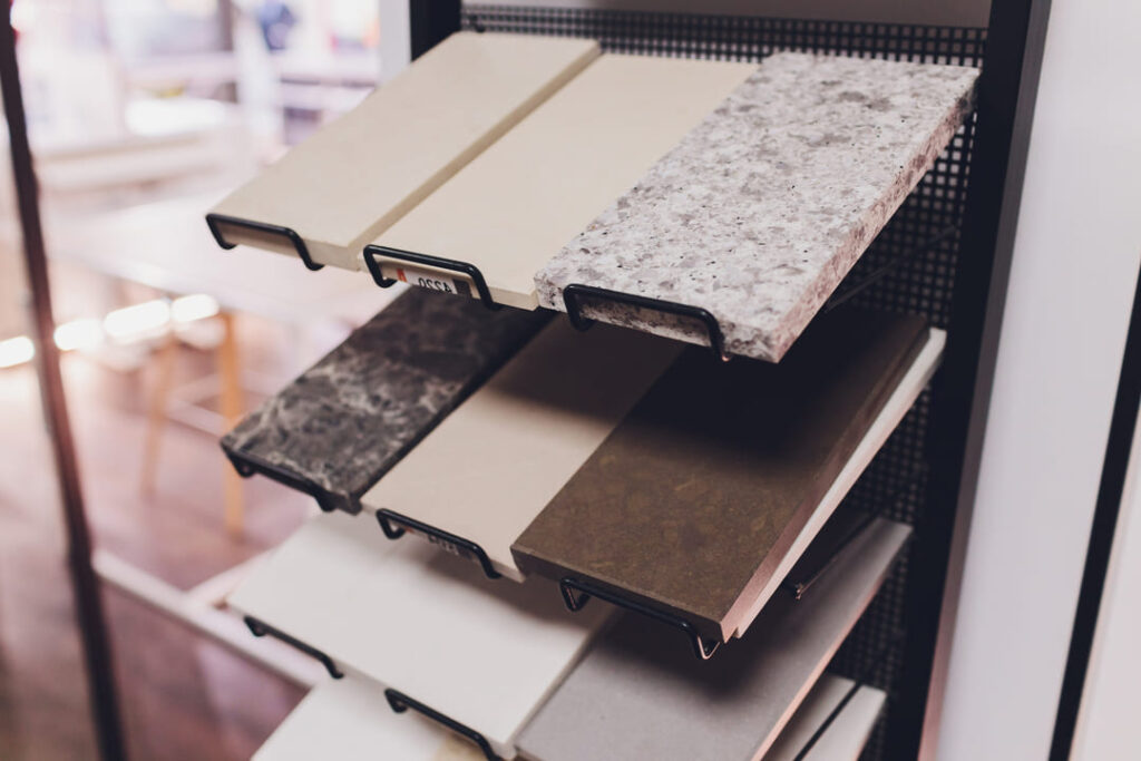 Amostras de m&aacute;rmore e granito em diferentes cores e acabamentos, organizadas em um expositor de metal.