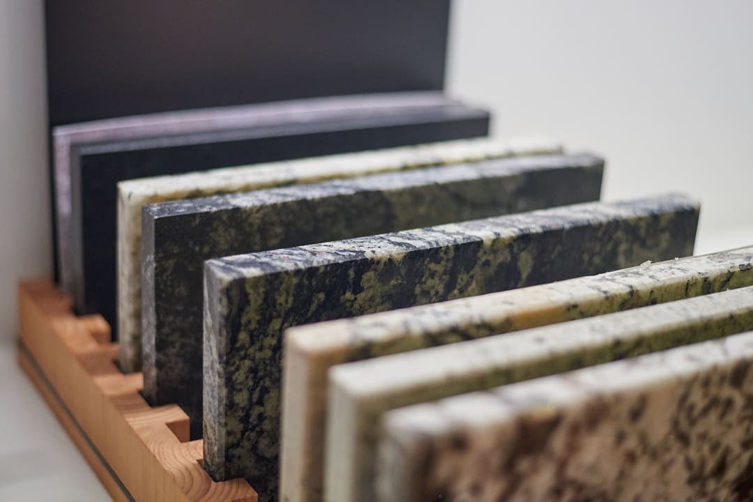 Amostras de mármore e granito em diferentes cores e texturas, organizadas em um expositor de madeira.