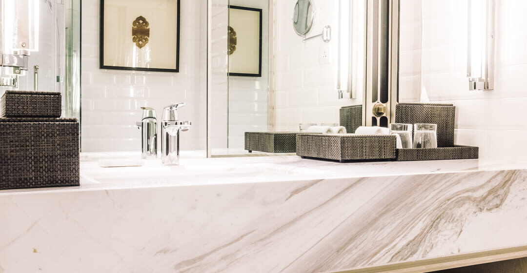 Bancada de banheiro feita com marmoglass branco, com acabamento elegante e detalhes em tons de cinza.