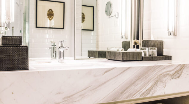 Bancada de banheiro feita com marmoglass branco, com acabamento elegante e detalhes em tons de cinza.