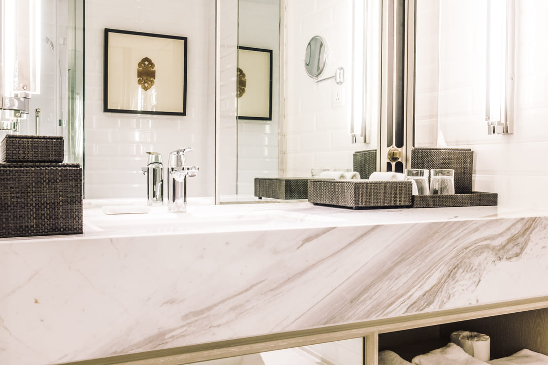 Bancada de banheiro feita com marmoglass branco, com acabamento elegante e detalhes em tons de cinza.