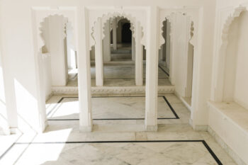 Interior de construção clara com piso de quartzito Taj Mahal e colunas com arcos ornamentados em estilo indiano.