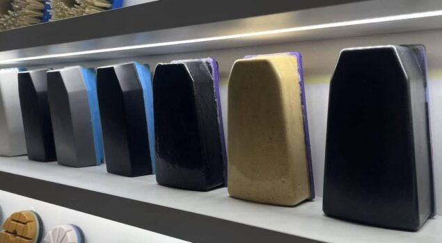 Imagem de uma prateleira com diversas ferramentas abrasivas de diferentes cores e texturas, usadas em processos de polimento. Os blocos indicam variações de granulometria, utilizadas conforme a etapa do polimento e o tipo de material.