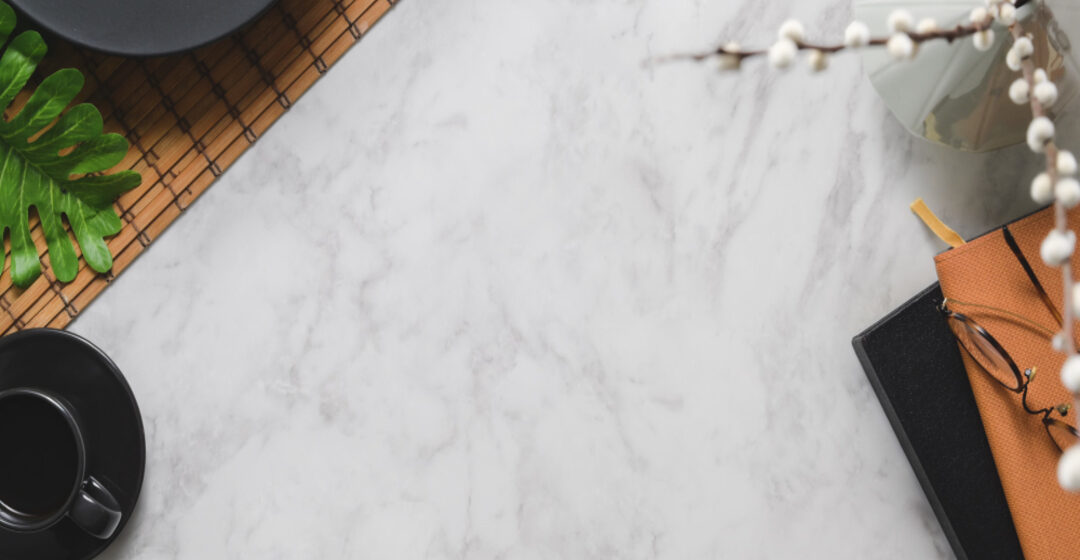 Superfície de pedra sintética clara com acabamento uniforme, vista de cima, utilizada como bancada em ambiente corporativo ou comercial.