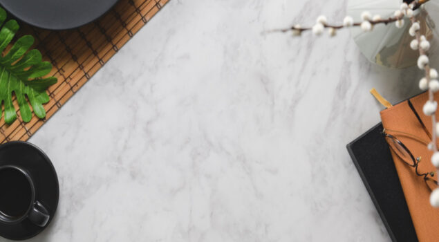 Superfície de pedra sintética clara com acabamento uniforme, vista de cima, utilizada como bancada em ambiente corporativo ou comercial.